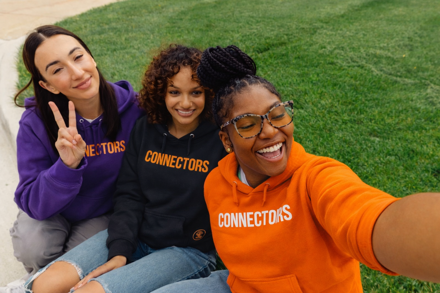 Connectors group selfie in purple, black, and orange hoodies
