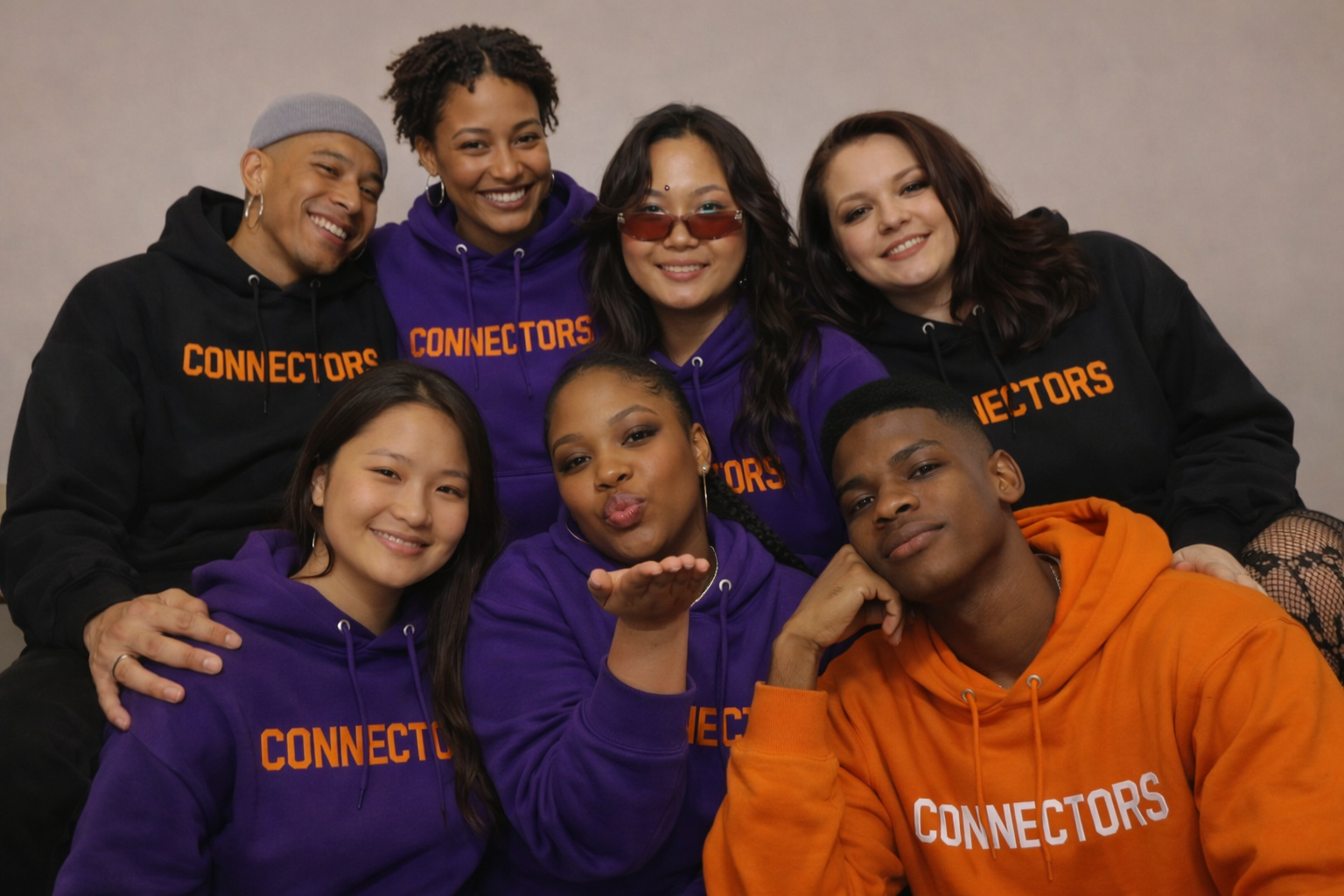 Connectors group portrait — seven members in purple, black, and orange hoodies