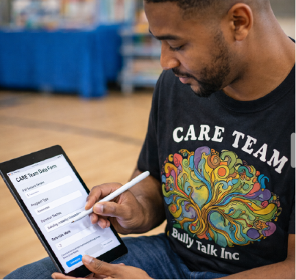CARE Team member in a CARE TEAM / Bully Talk Inc. shirt talking with a semicircle of young students on a library floor