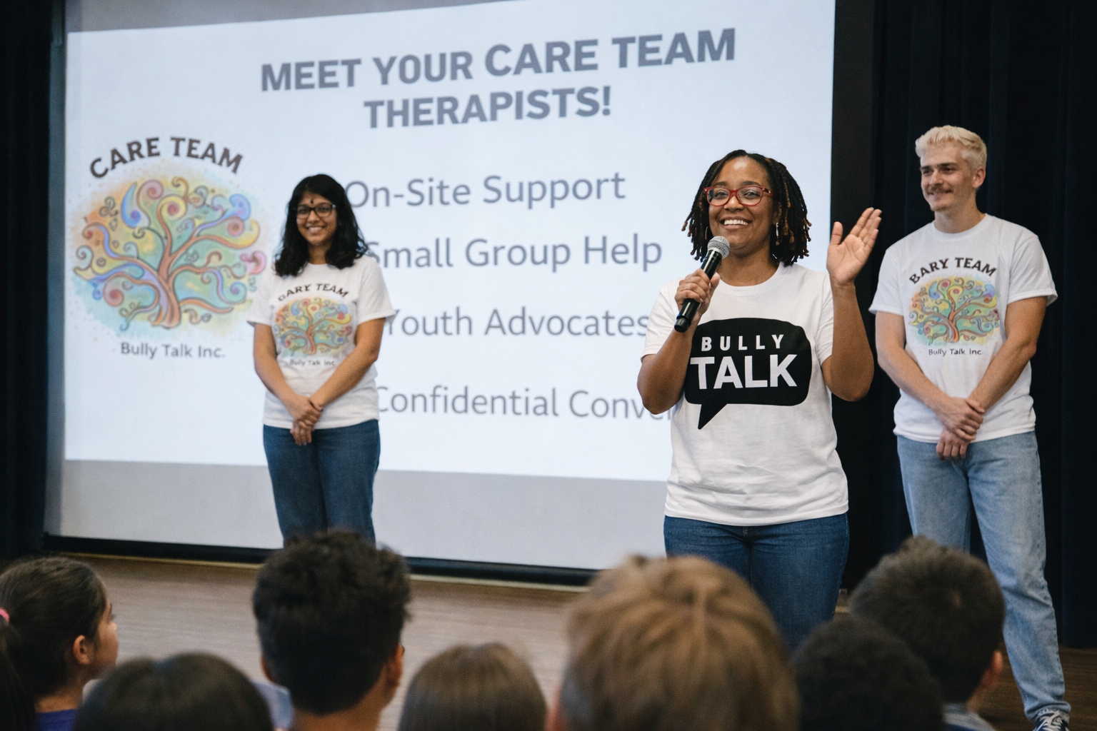 CARE Team therapists on stage at a school assembly introducing themselves to students