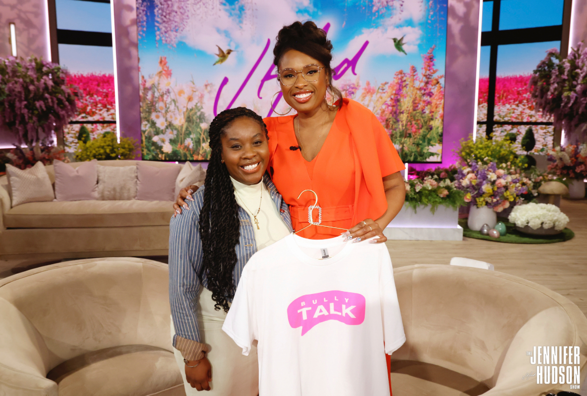 Kina Evans surprised by Jennifer Hudson on The Jennifer Hudson Show, holding a Bully Talk t-shirt on a TV studio set